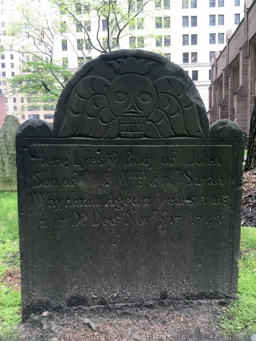 A slate tombstone with a skull effigy on it